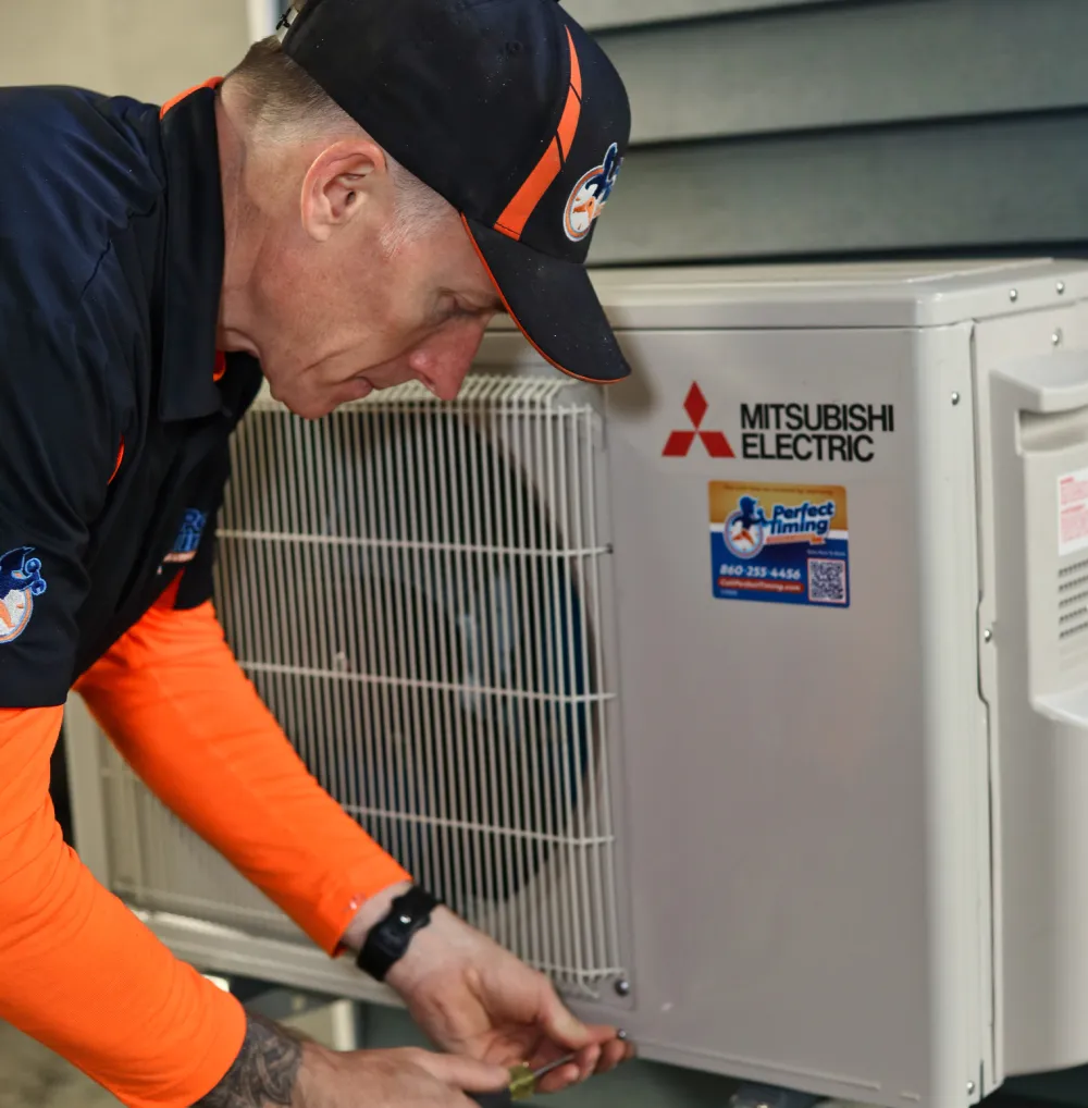 Perfect Timing Heating & Cooling technician performing heat pump repair and maintenance on a Mitsubishi Electric heat pump system