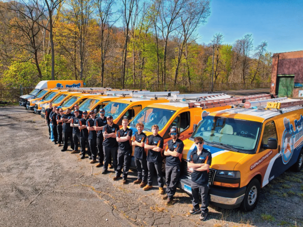 Perfect Timing Heating and Cooling team standing in front of branded HVAC service vehicles representing heating and cooling services in Burlington, CT.